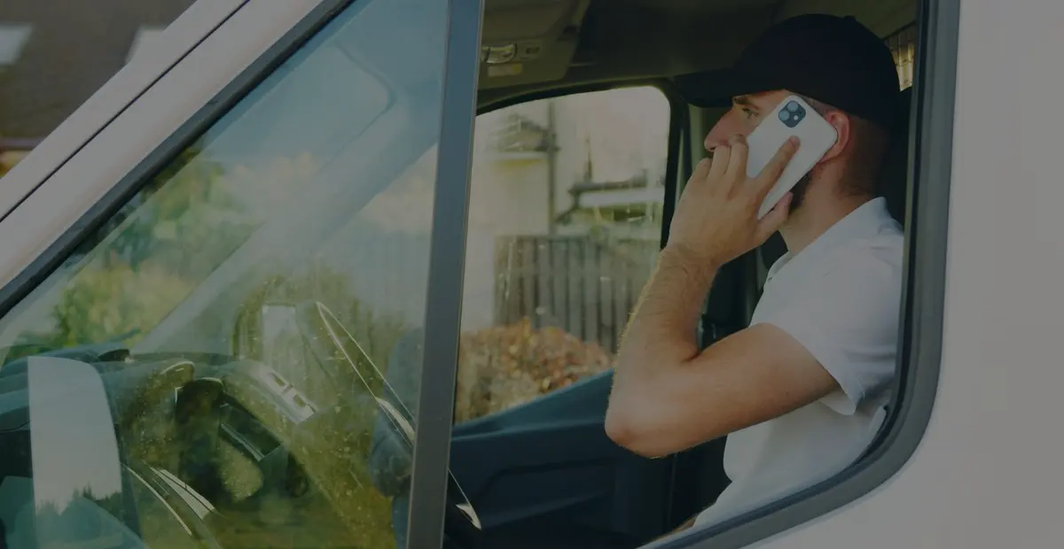 A tradesperson taking a phone call from the cab of a work van.